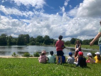 Groupe d'enfants assis dans l'herbe devant un lac